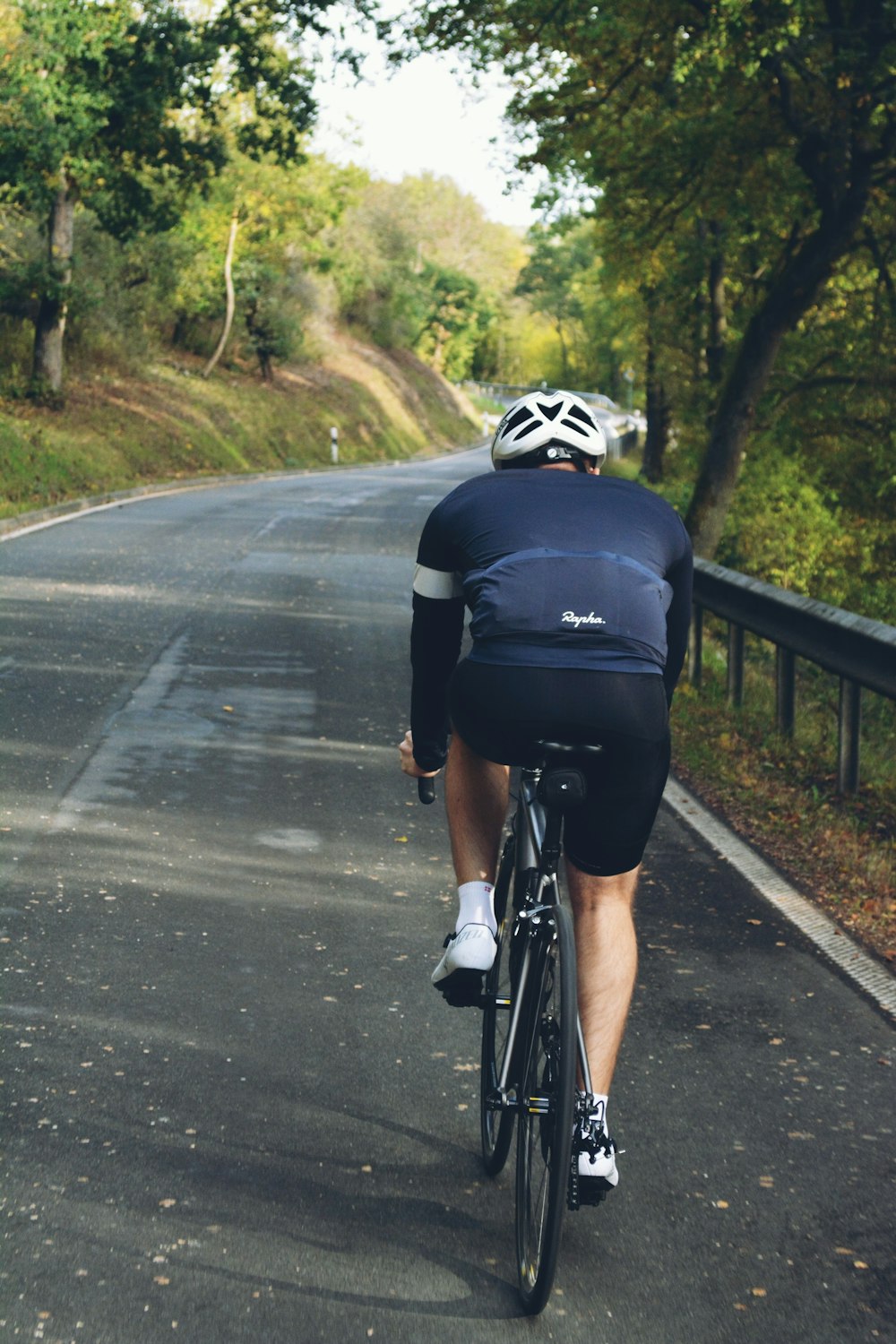 hombre en camisa negra montando en bicicleta en la carretera durante el día