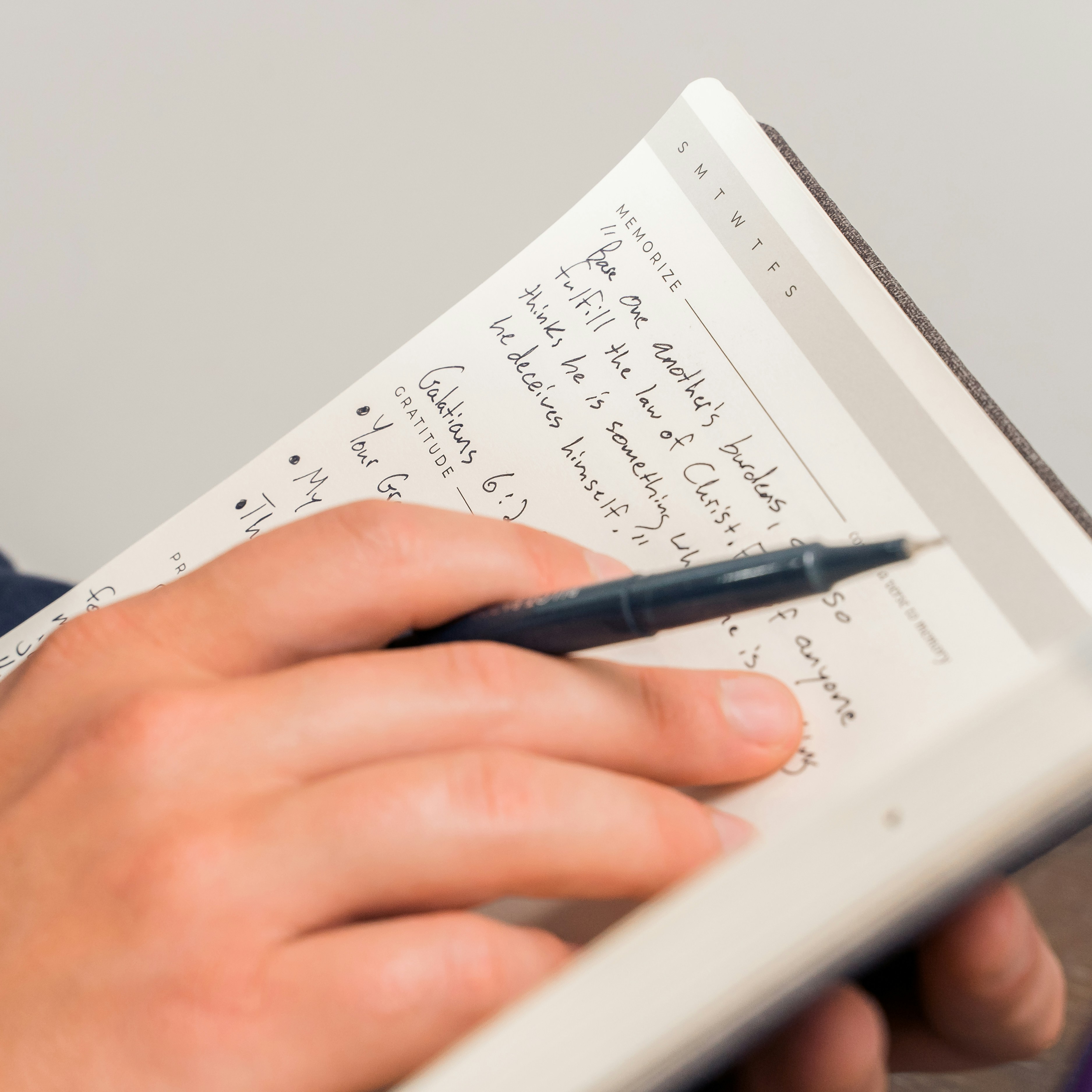 personne écrivant sur du papier blanc