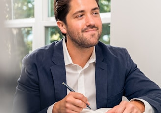 man in black suit jacket holding pen