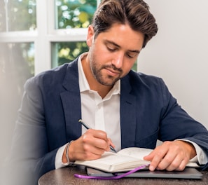 man in blue suit jacket holding white tablet computer