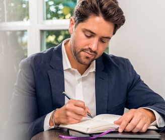 man in blue suit jacket holding white tablet computer