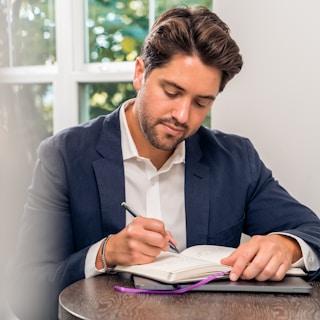 man in blue suit jacket holding white tablet computer