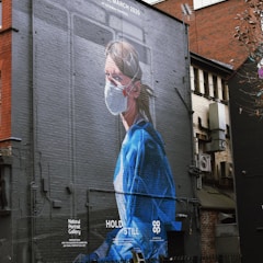 woman in blue dress standing near building during daytime