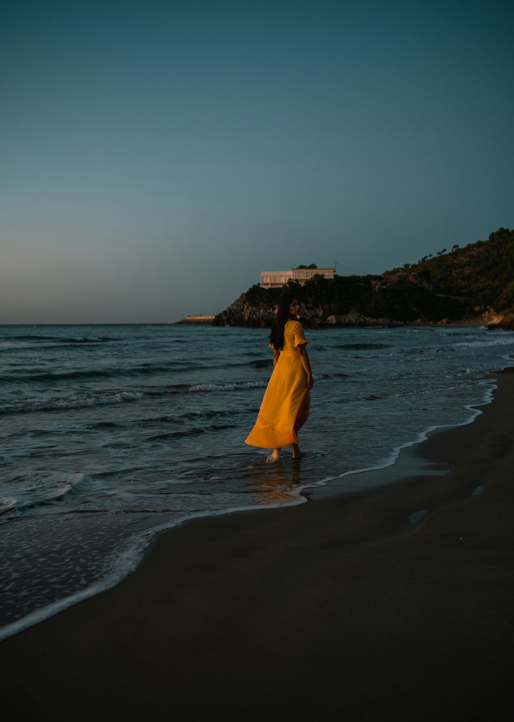 woman in yellow dress standing on beach during daytime