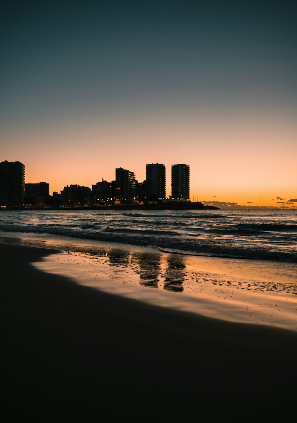 silhouette of city buildings near sea during sunset