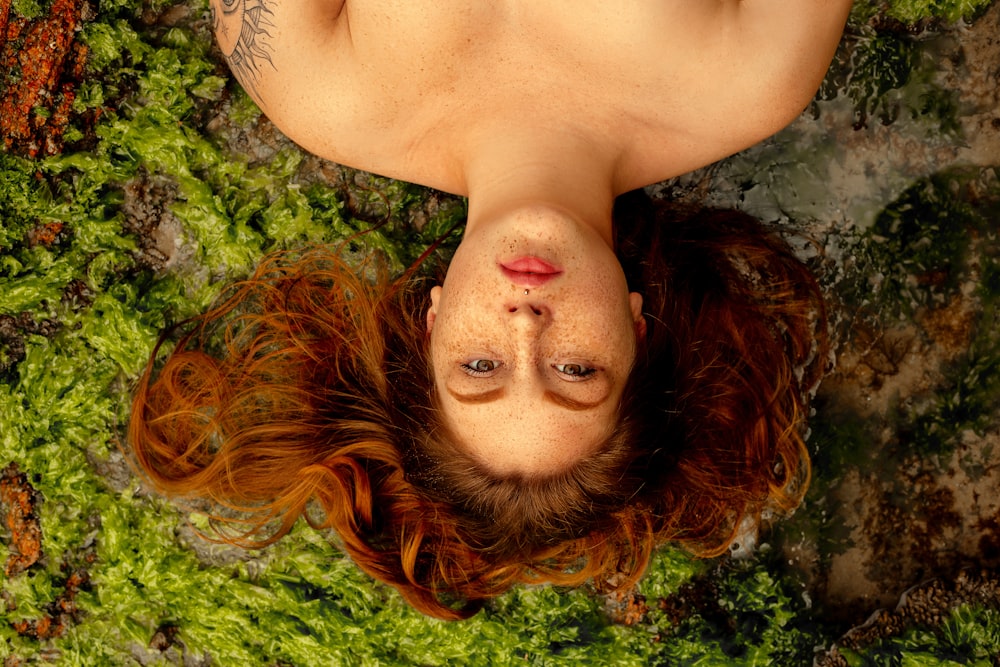 woman with orange hair lying on green moss