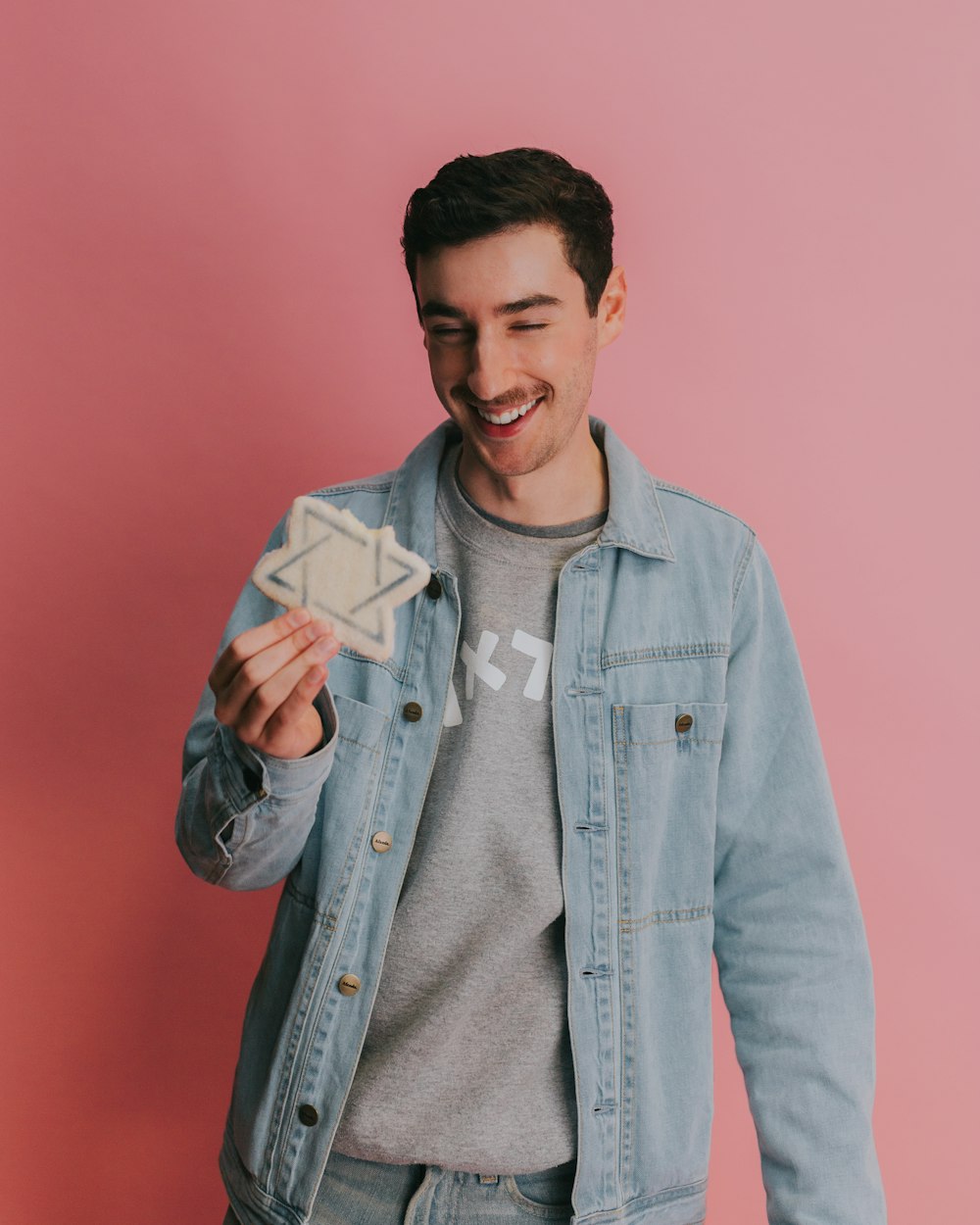 man in blue denim button up jacket holding white card