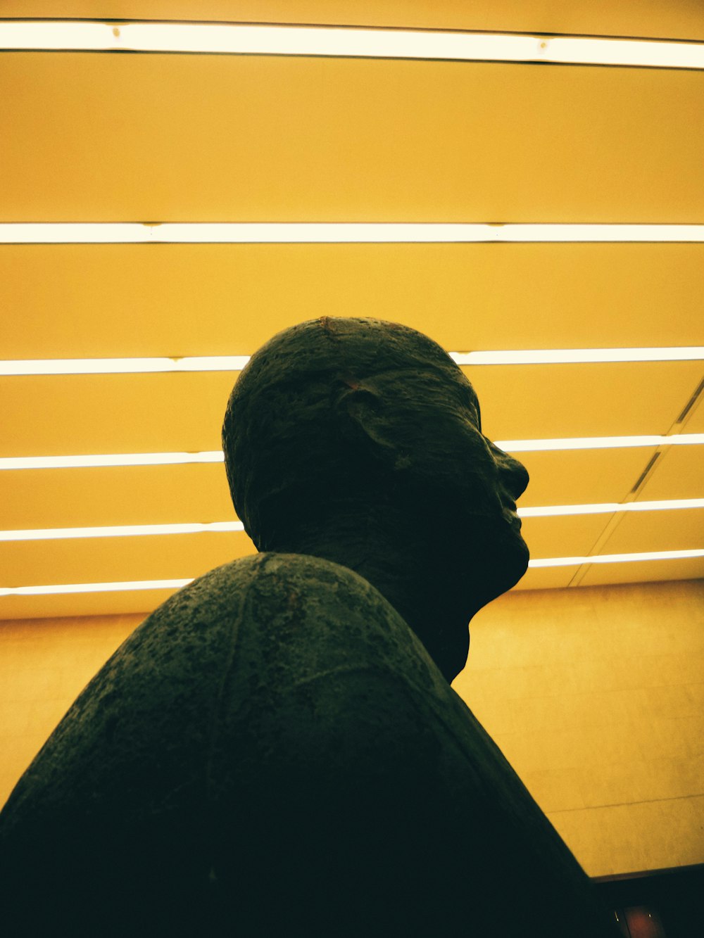 man in black hoodie standing beside yellow wall