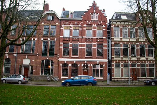 blue car parked in front of brown concrete building