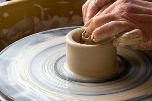 Close-up of hands shaping a clay pot on a pottery wheel in a cozy studio.