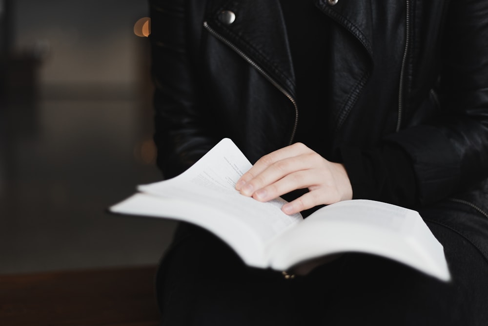 person in black leather jacket holding white paper