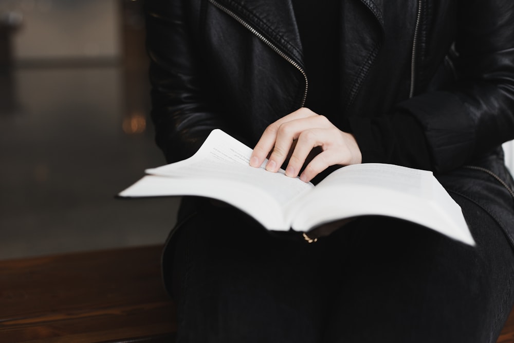 a woman sitting on a bench reading a book