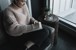 A person journaling, with a warm coffee beside them – capturing a gentle self-care routine.