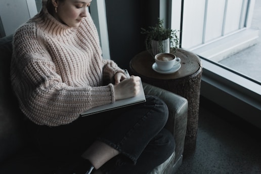 A person journaling, with a warm coffee beside them – capturing a gentle self-care routine.