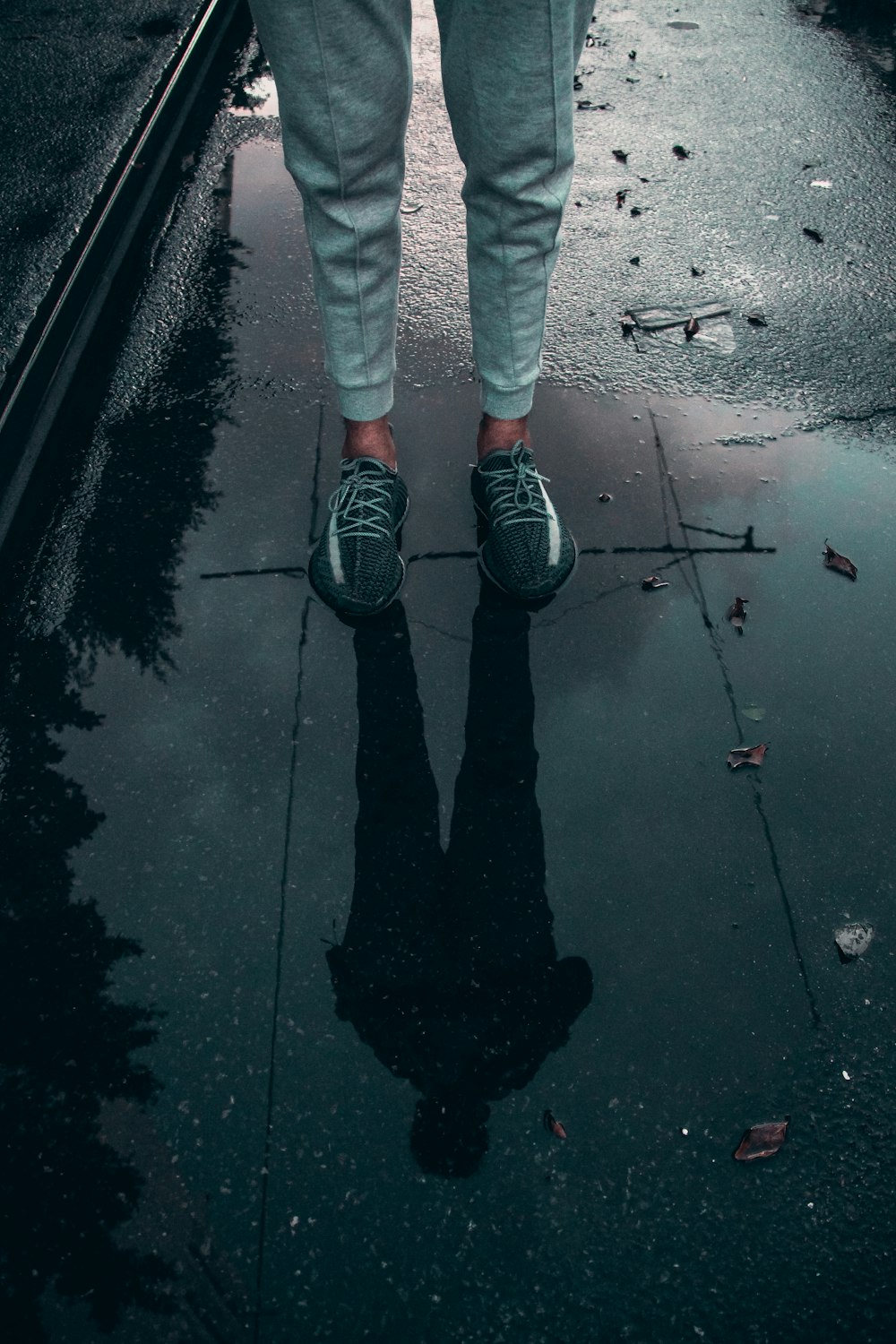 person in blue denim jeans and black sneakers standing on wet ground