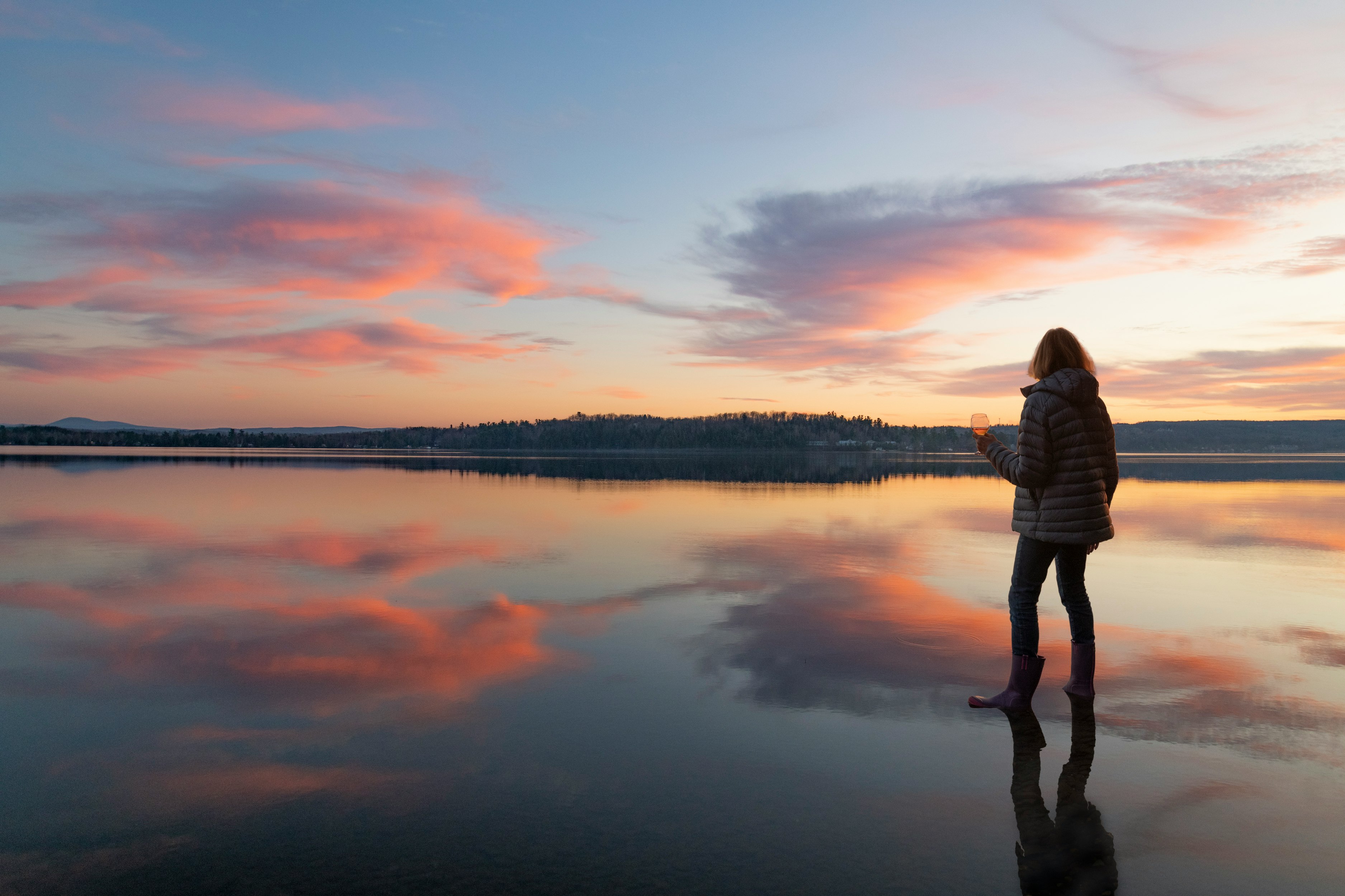 woman in white long sleeve shirt standing near lake during sunset