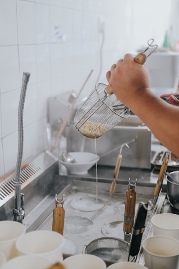 A sleek sink drainer basket holding drying dishes in a bright, modern kitchen.