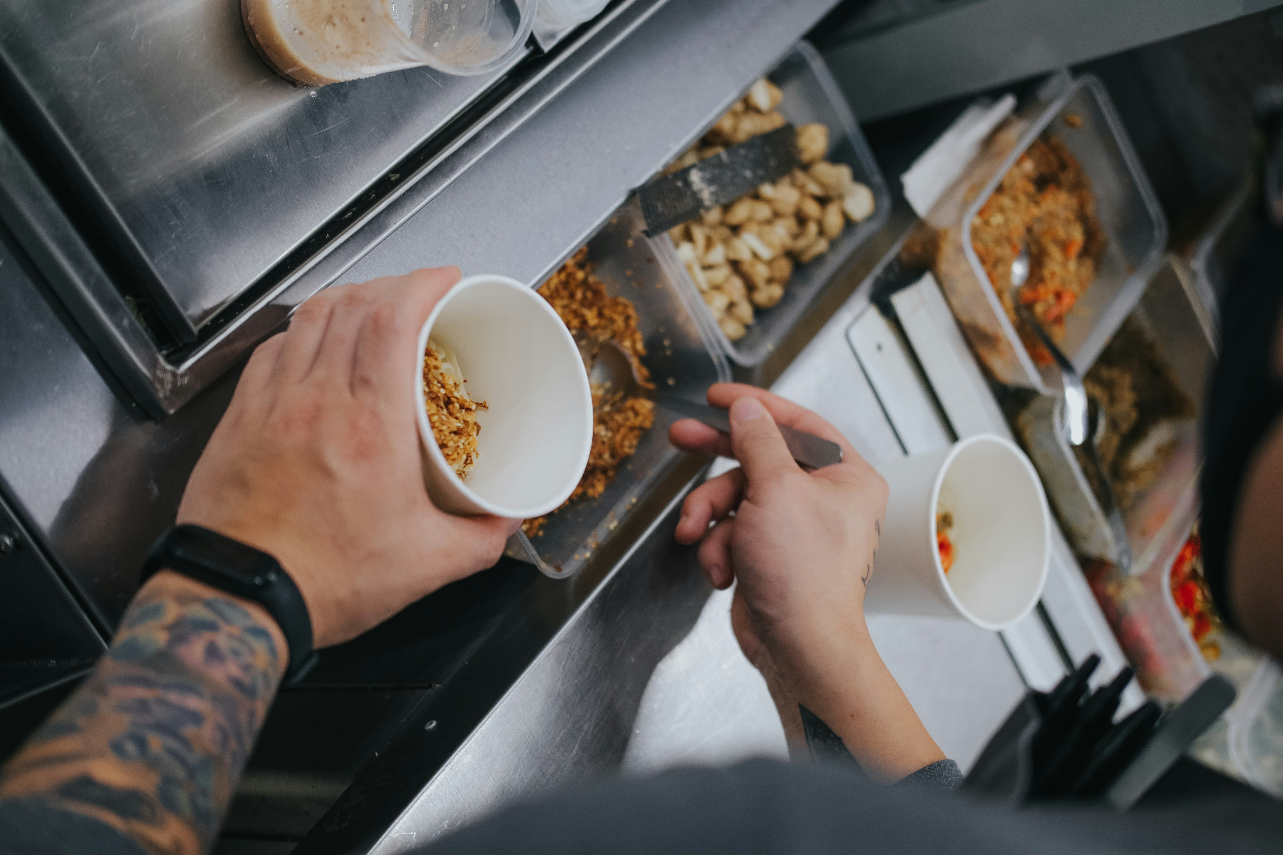 Hands holding two takeaway bowls of food