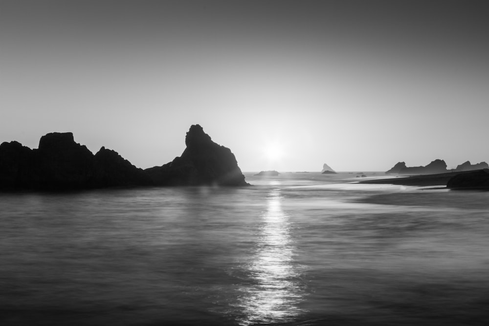 grayscale photo of rock formation on sea