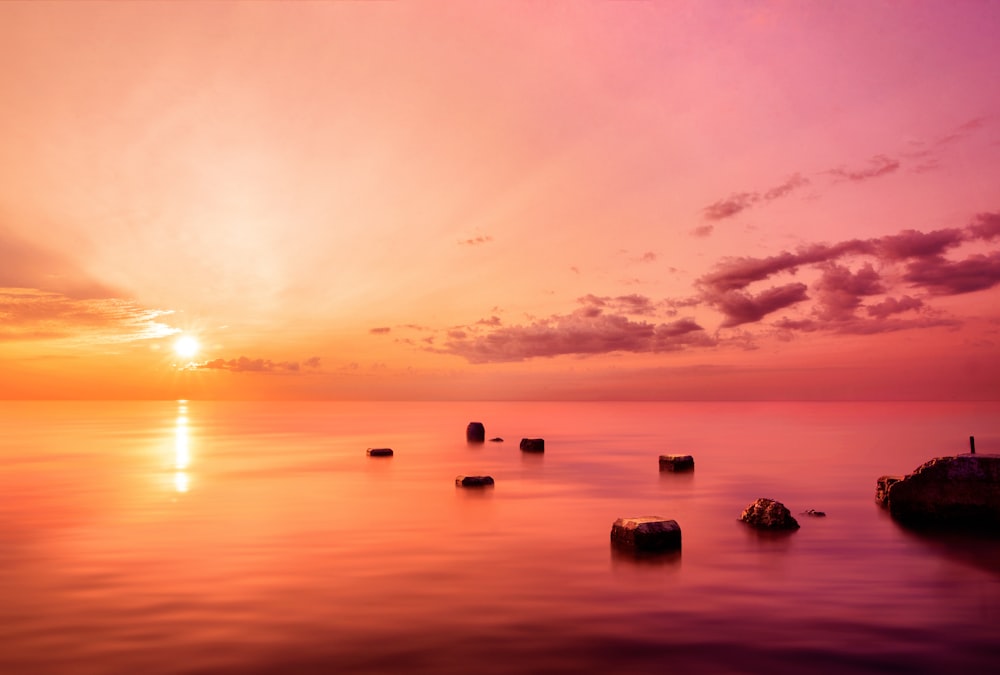 silhouette of rocks on sea during sunset