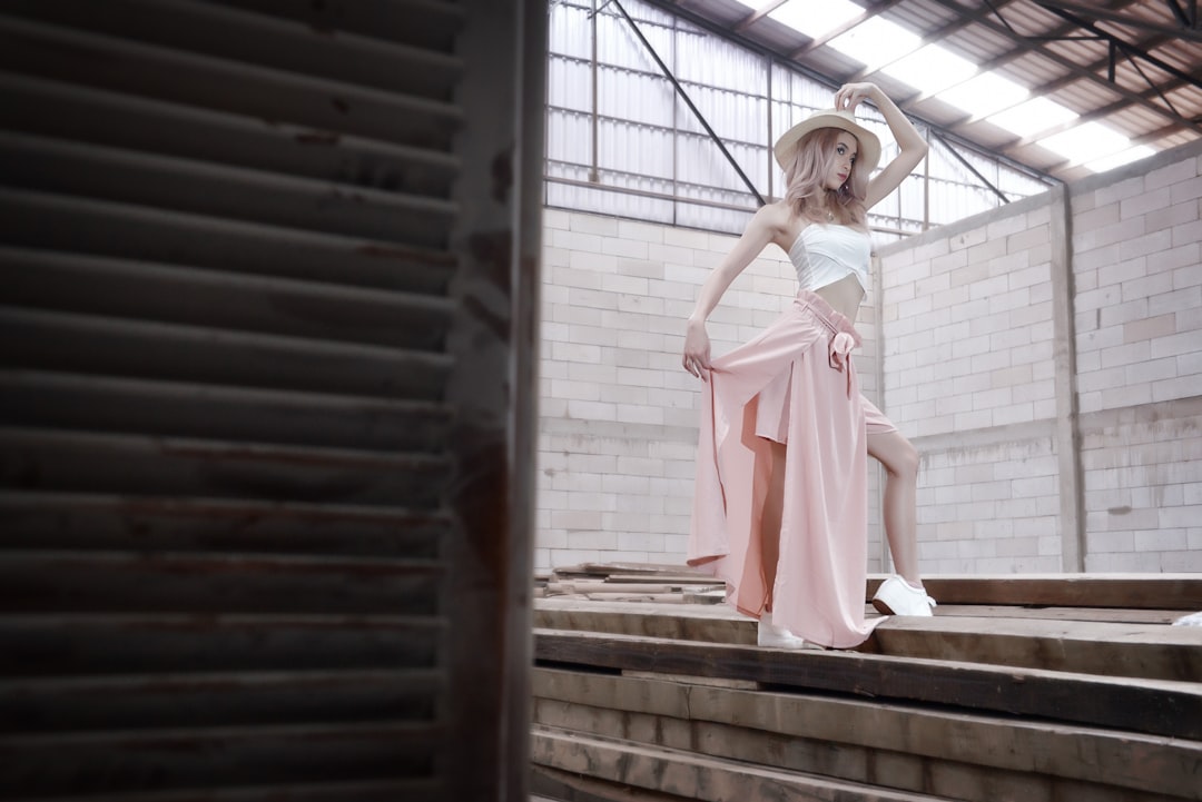 woman in pink dress standing on brown wooden stairs