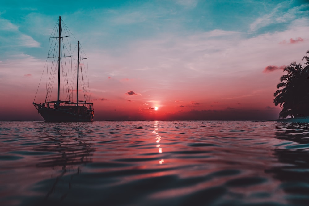 silhouette of boat on sea during sunset