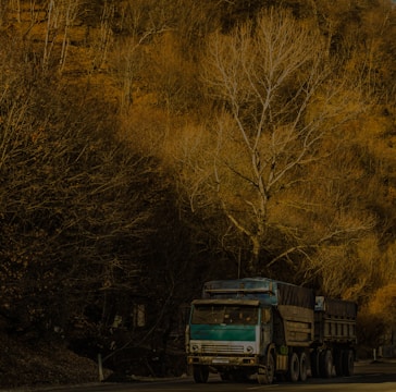 A powerful green and yellow truck driving on a highway surrounded by lush landscapes