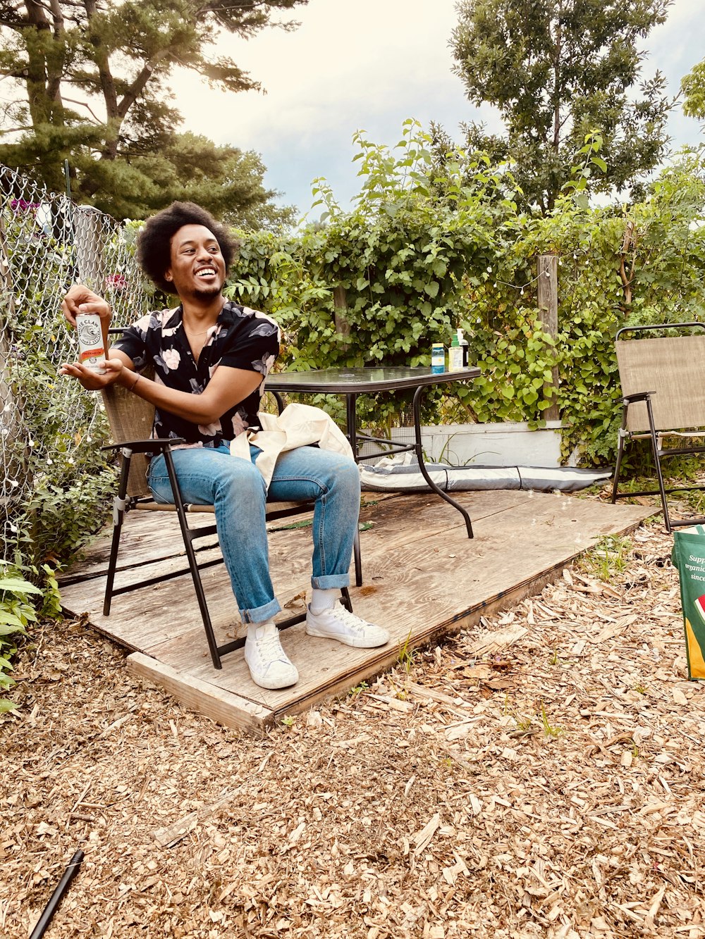 woman in black jacket and blue denim jeans sitting on brown wooden bench