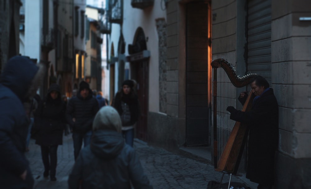 Hombre tocando un instrumento musical cerca de la pared de ladrillo marrón durante el día