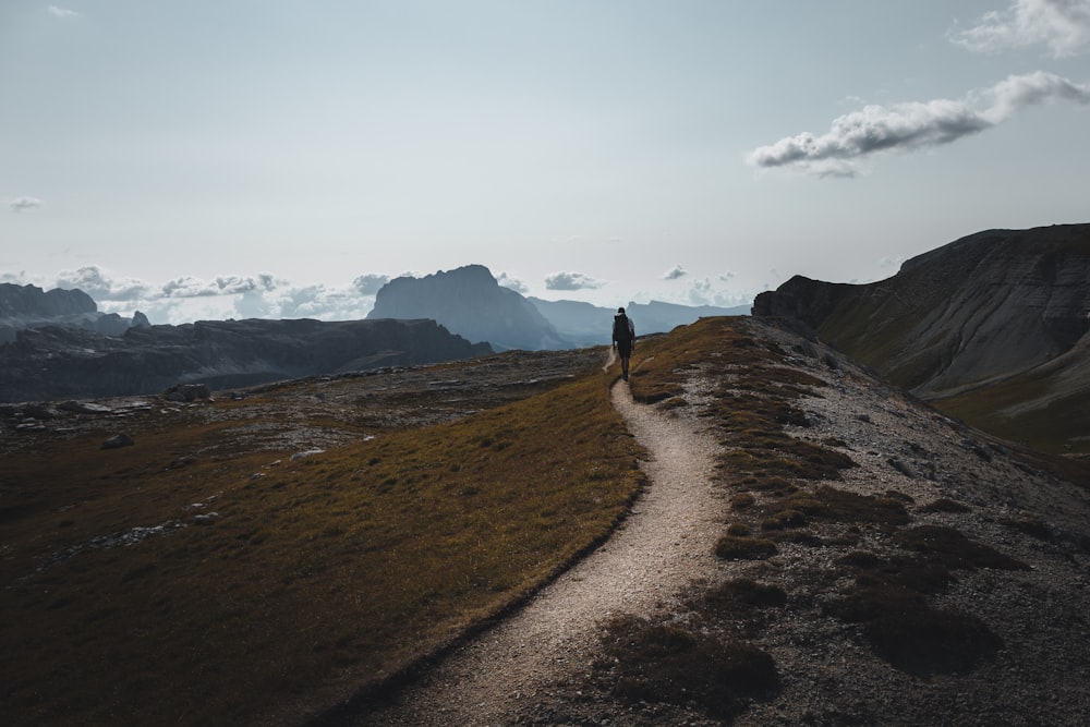 person walking on brown dirt road during daytime