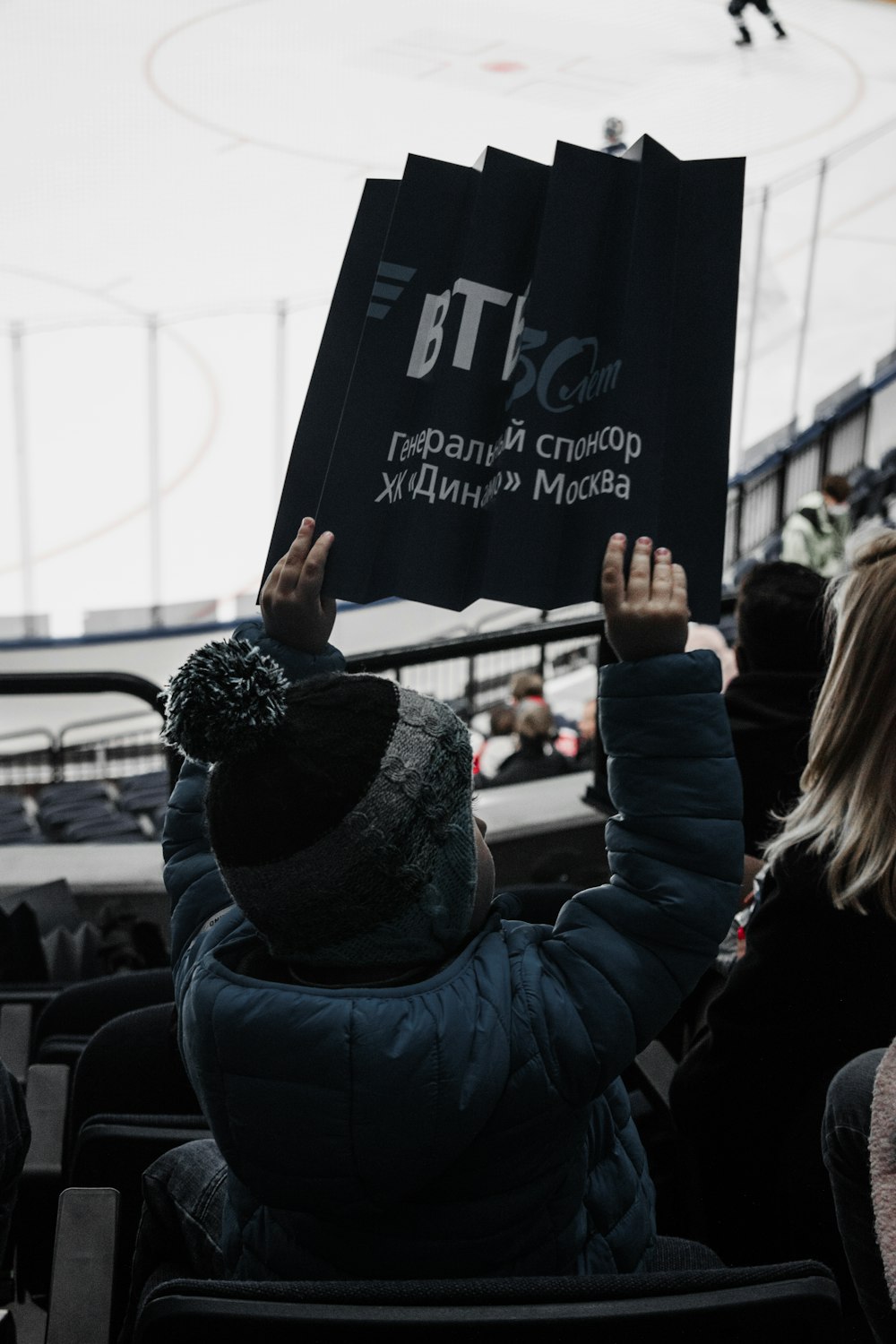 woman in blue jacket holding black banner