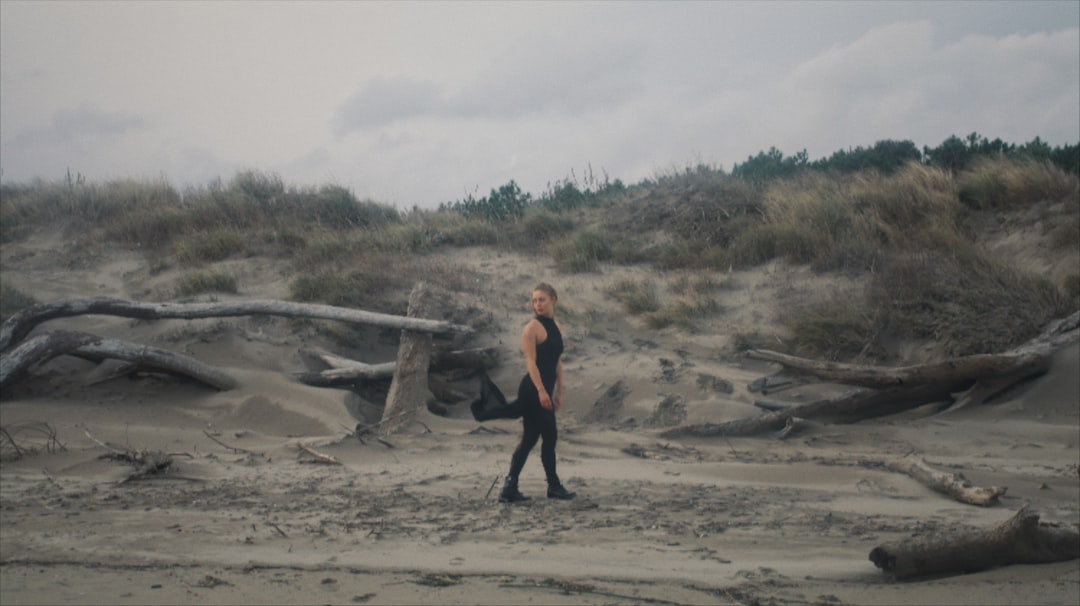 woman in black tank top and black pants standing on brown sand during daytime