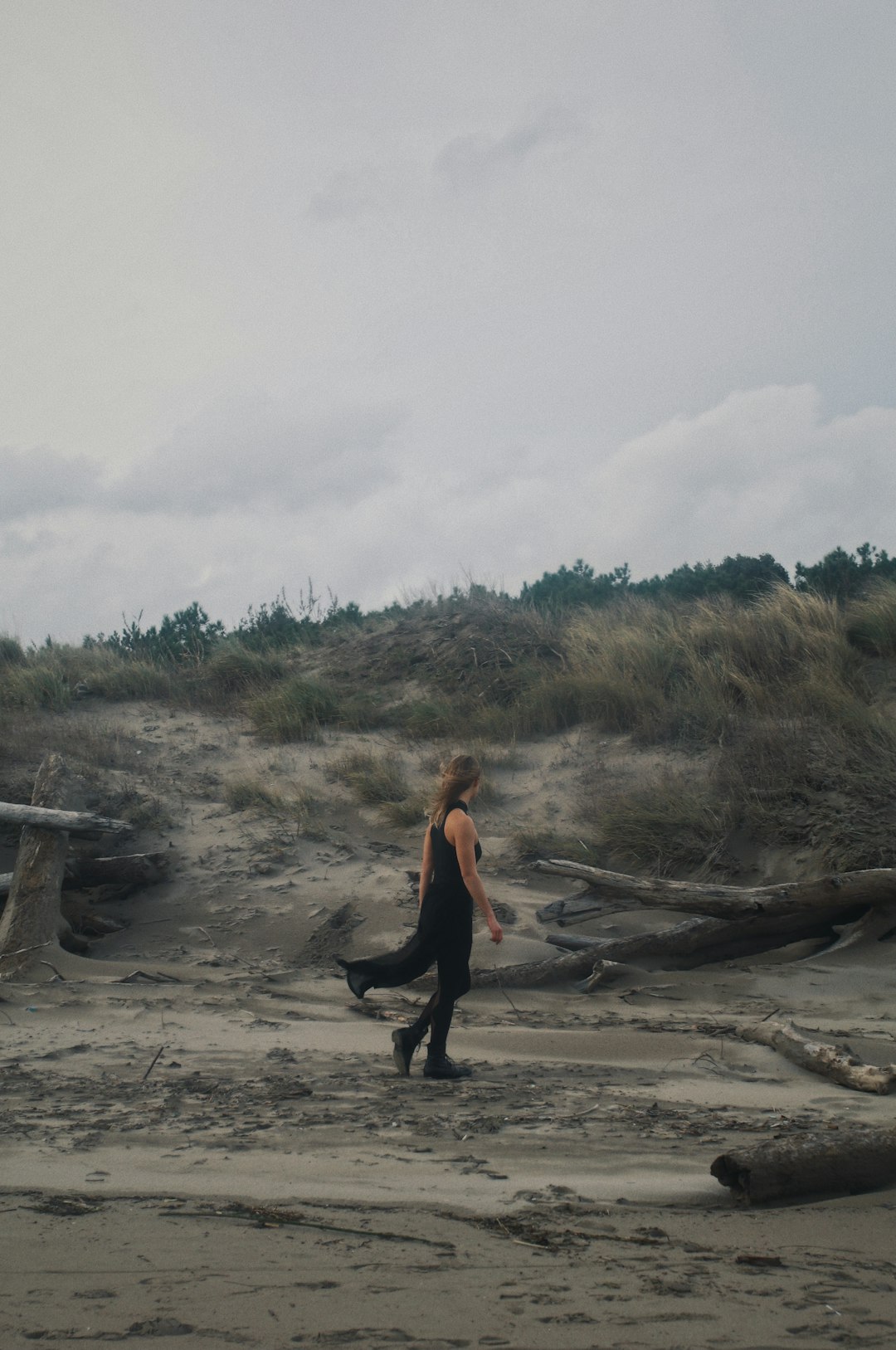 woman in black pants and black boots sitting on brown log during daytime