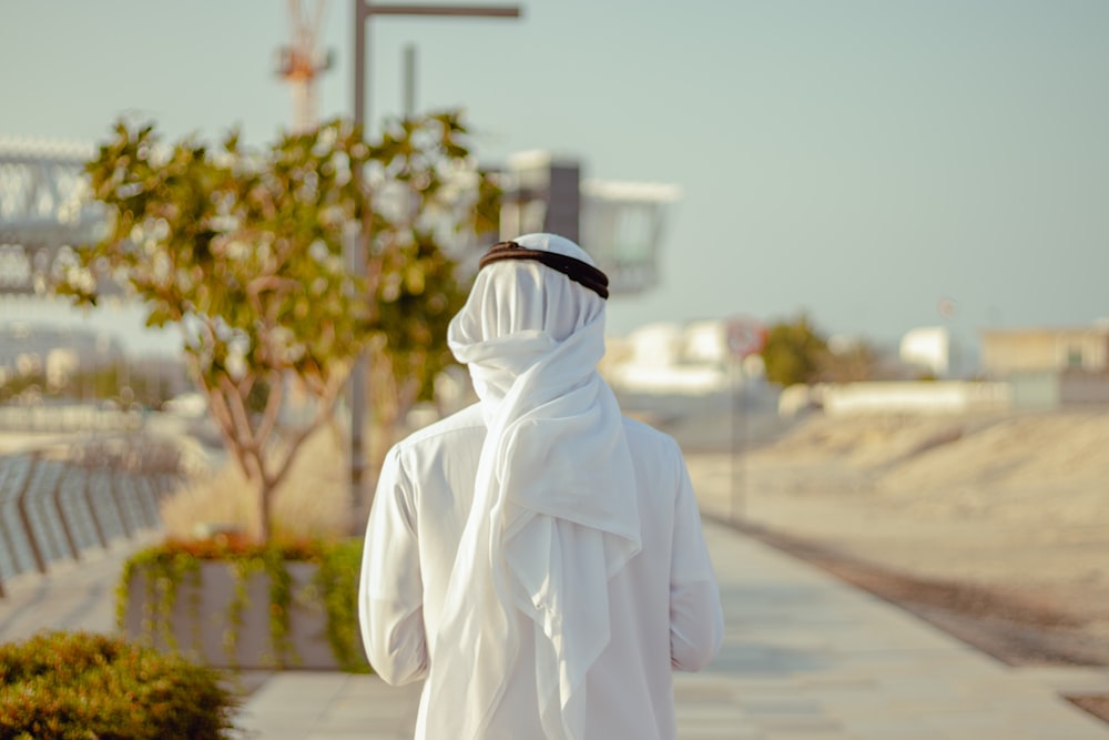 person in white robe standing on road during daytime