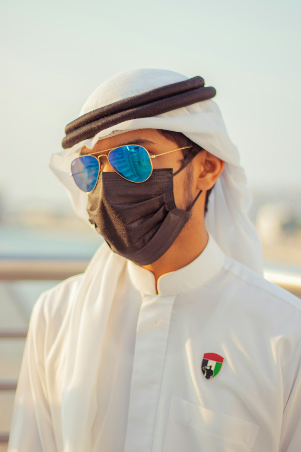 Homme en chemise blanche boutonnée portant des lunettes de soleil noires et un chapeau marron