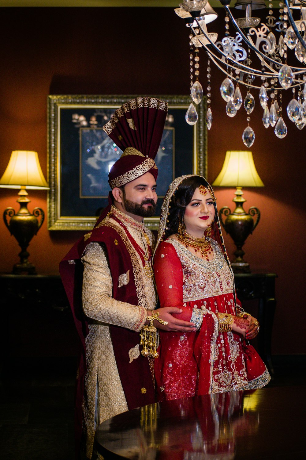 woman in red and white sari standing beside brass and white table lamp