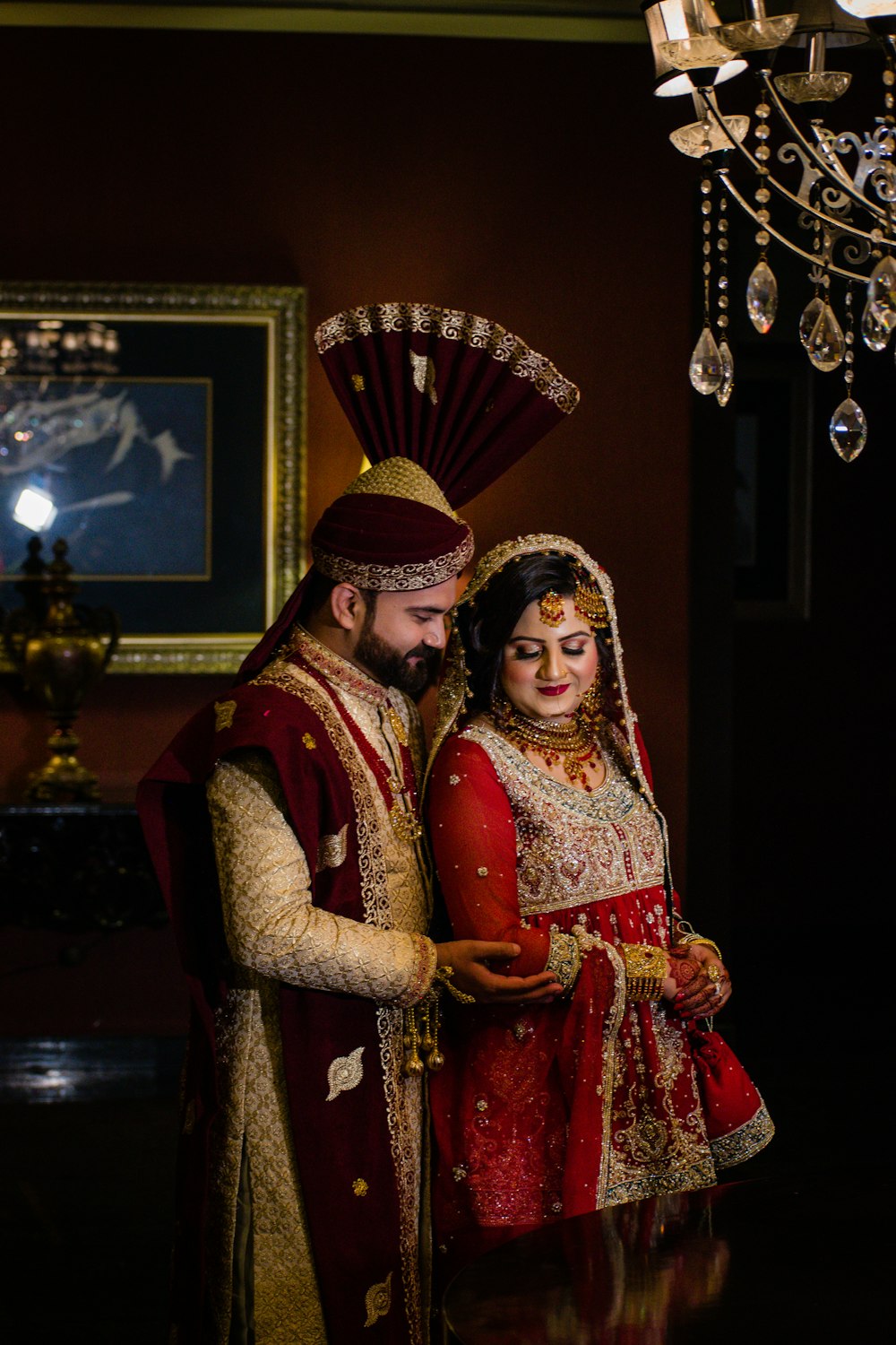 woman in red and gold sari standing beside woman in red and gold sari