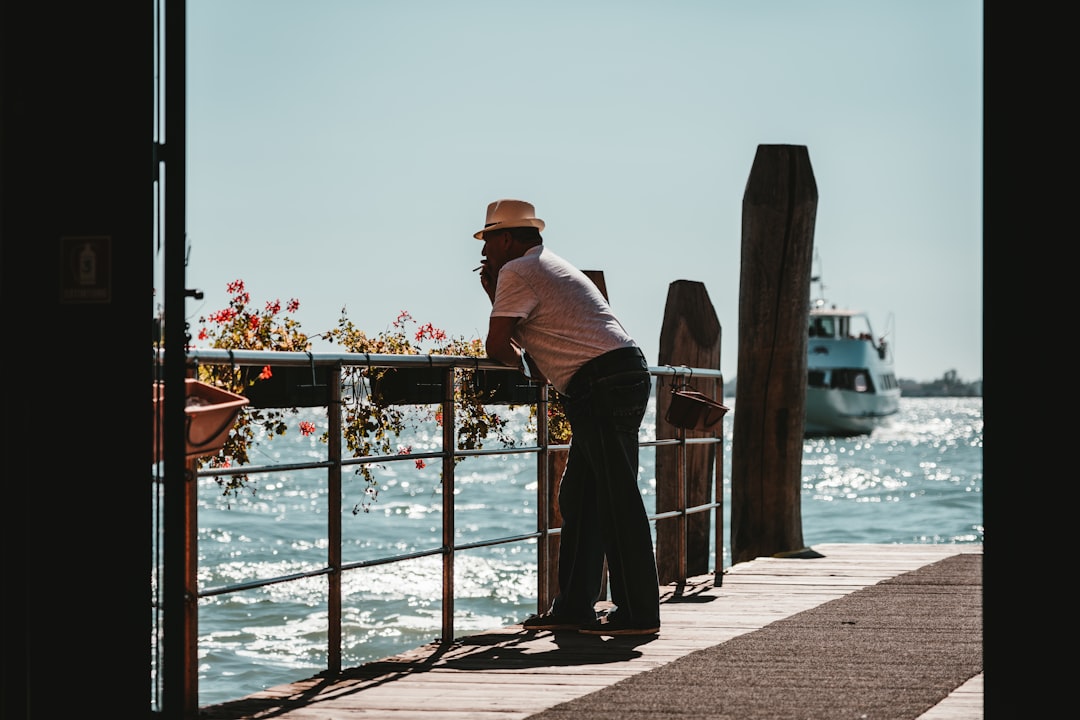 man in black long sleeve shirt and brown hat standing beside railings during daytime