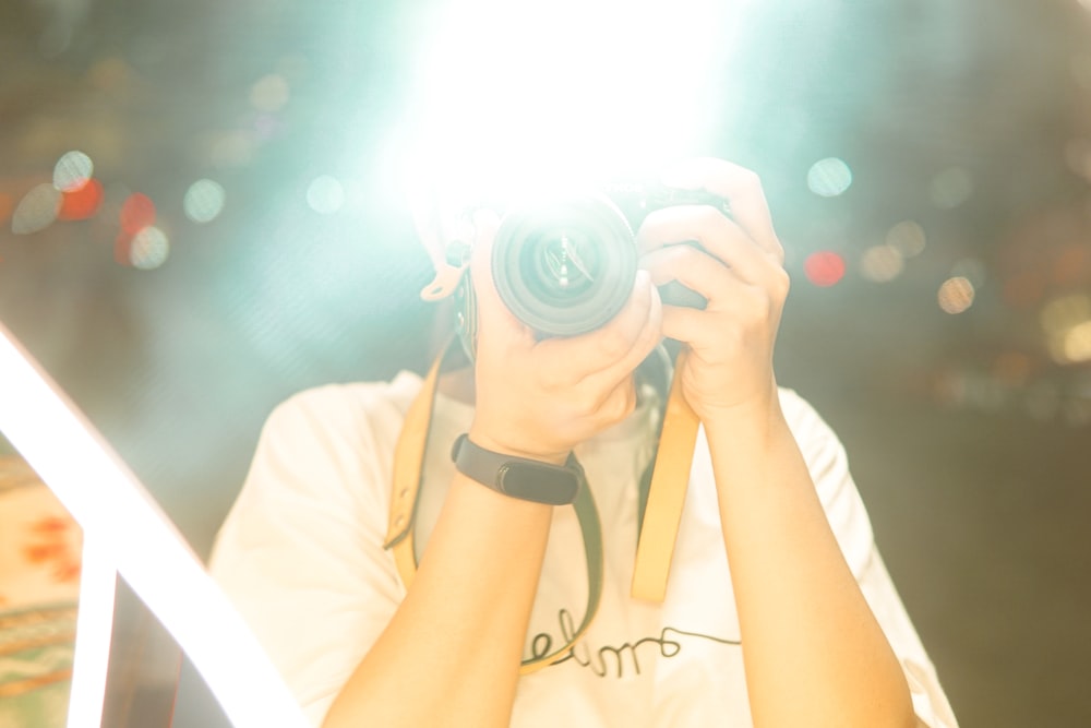 woman in white t-shirt holding black dslr camera