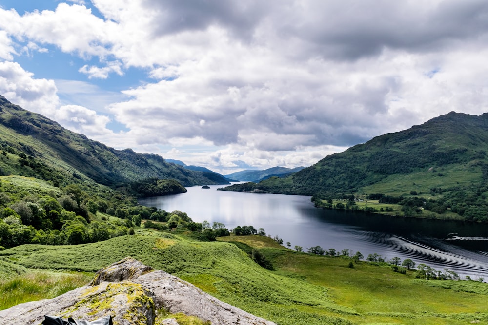 campo de hierba verde cerca del lago bajo el cielo nublado durante el día