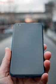 Close-up of a hand holding a smartphone with the bg remove app open, showing background removal in progress.