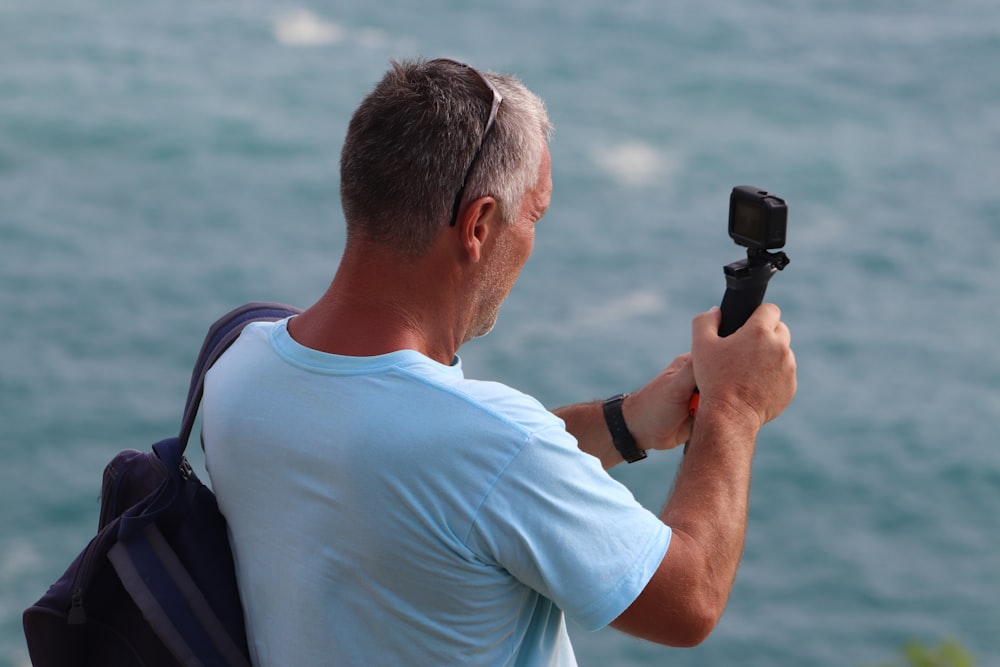 man in white crew neck t-shirt holding black smartphone