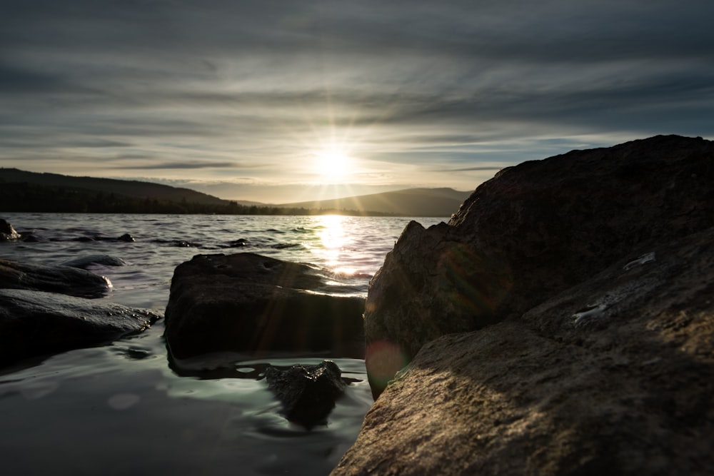 brown rock formation on body of water during sunset