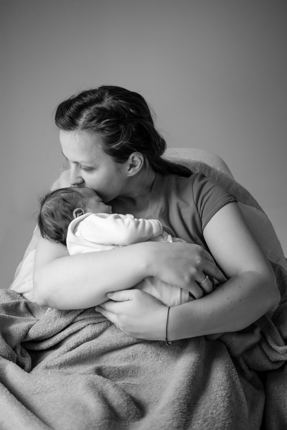 Foto en escala de grises de una mujer en camiseta con un bebé en brazos.