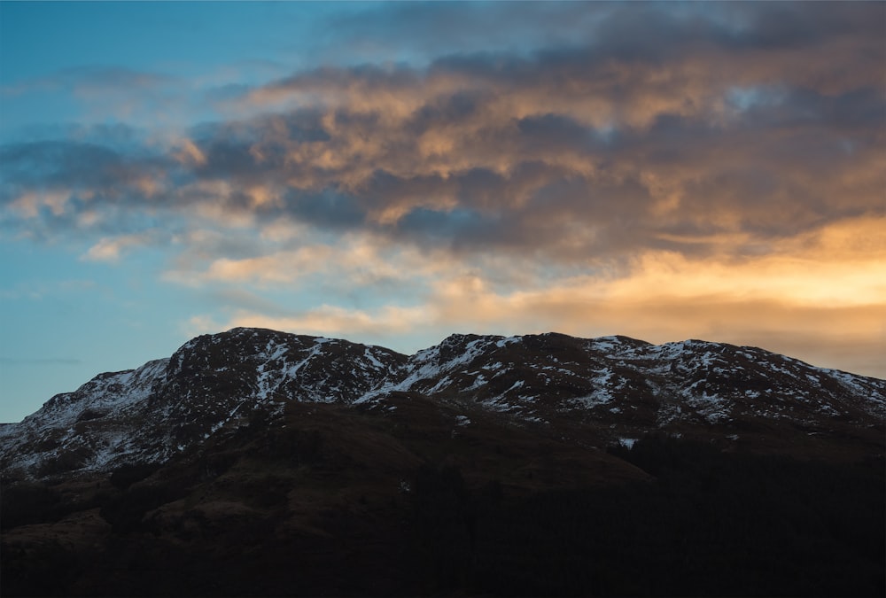 montagne brune et noire sous ciel nuageux pendant la journée