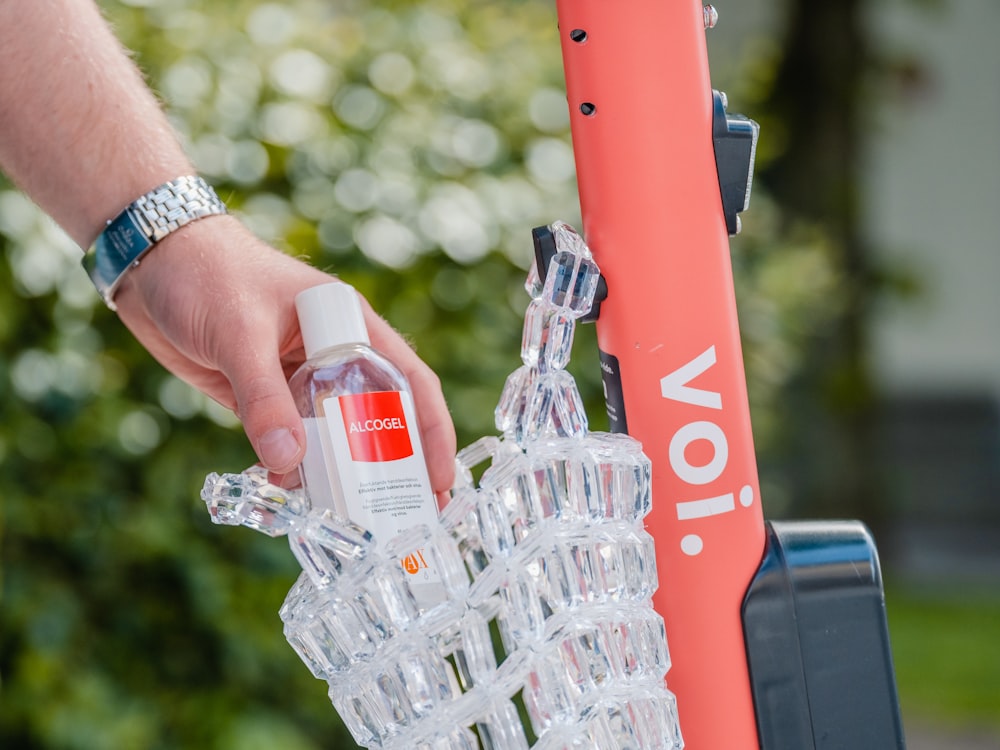 person holding clear glass bottle