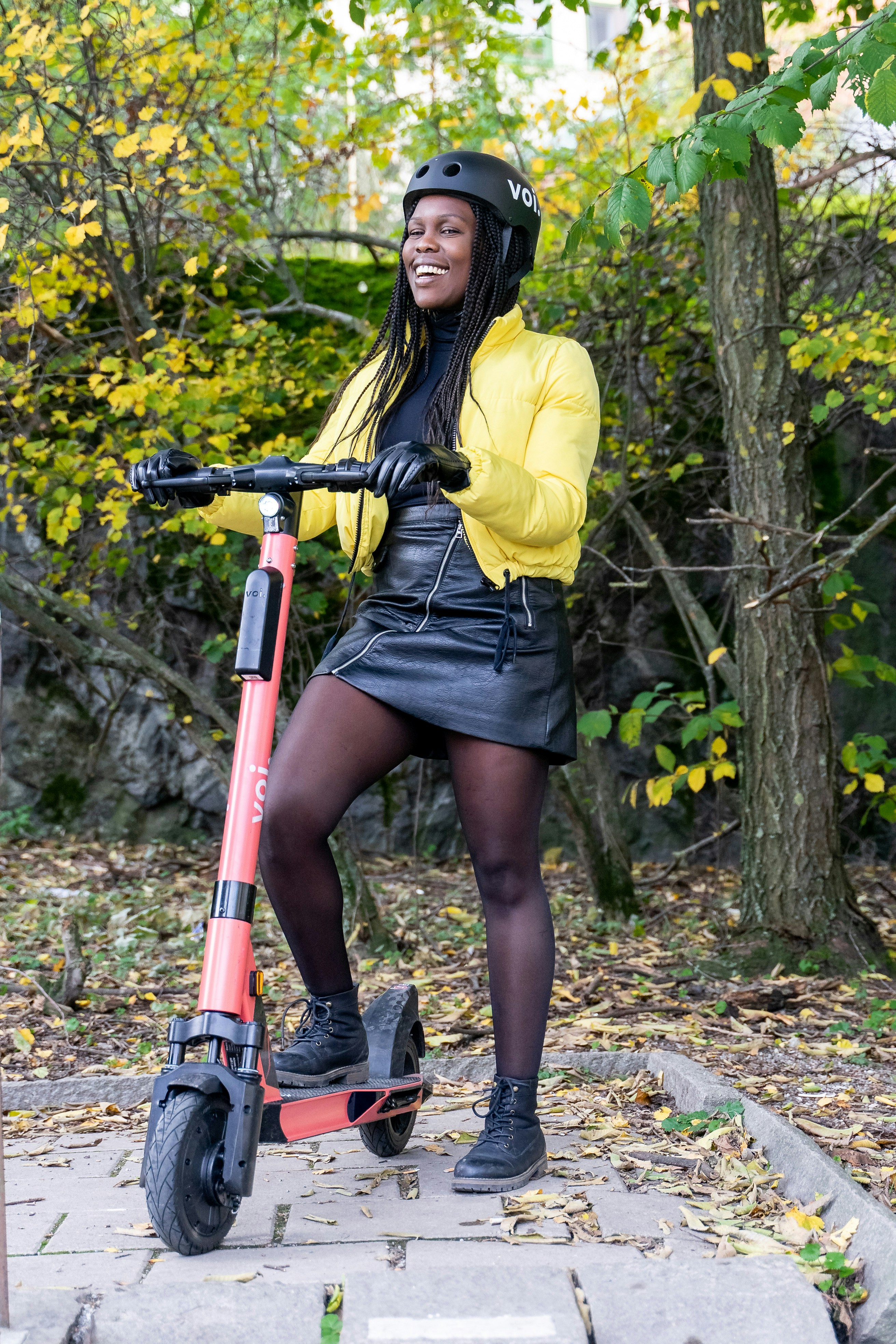 黄色の長袖シャツと黒のスカートを着た女性が赤と黒の自転車を持っている