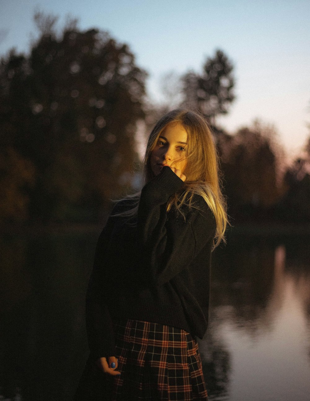 woman in black jacket standing near body of water during daytime