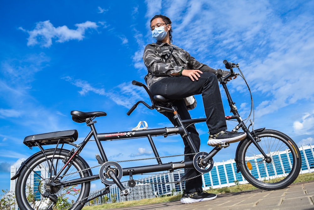 Femme en veste noire circulant sur un vélo noir pendant la journée