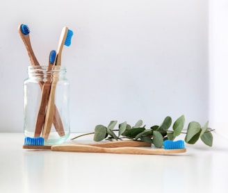 blue and white toothbrush in clear glass jar